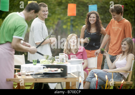 Un gruppo di giovani su un giardino con barbecue Foto Stock