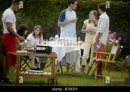 Un gruppo di giovani su un giardino con barbecue Foto Stock