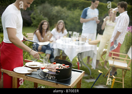 Un gruppo di giovani su un giardino con barbecue Foto Stock