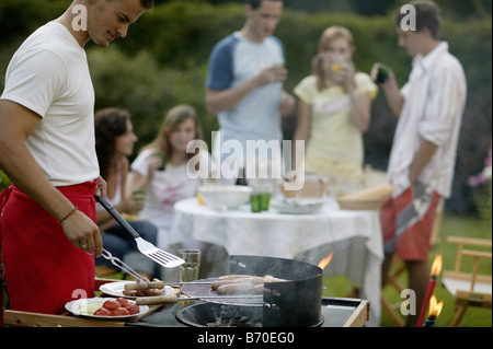 Un gruppo di giovani su un giardino con barbecue Foto Stock