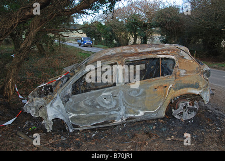 Una vettura incidentata e bruciato in una corsia rurale in cornwall, Regno Unito Foto Stock