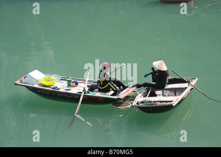 Fotografia di due donne in barca in chat con le loro barche nella baia di Halong, Vietnam Foto Stock