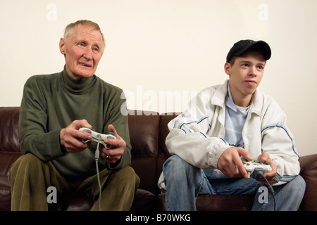 Un adolescente giocando su una console di giochi Xbox (360) con un uomo più anziano Foto Stock