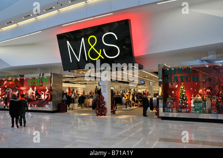 Finestra del negozio al dettaglio Marks and Spencer e segno M&S rosso illuminato sul retro sopra l'entrata nel centro commerciale Westfield Shepherds Bush White City Londra Inghilterra Regno Unito Foto Stock