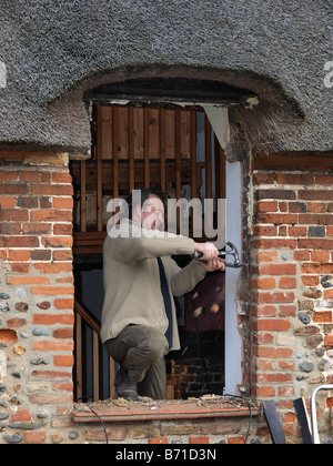 Nuova finestra essendo montato sul vecchio cottage con il tetto di paglia HAPPISBURGH NORFOLK East Anglia England Regno Unito Foto Stock