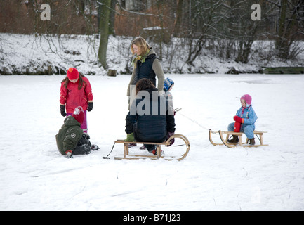 Famiglia in appoggio su un lago ghiacciato con slittini Foto Stock