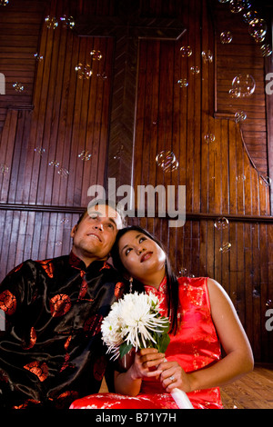 Coppia giovane indossando il tradizionale abbigliamento asiatici guardare fino a bolle Foto Stock