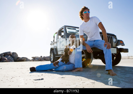 Giovani interracial giovane seduto vicino a jeep a beach Foto Stock
