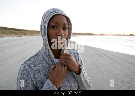 Giovane americano africano donna che indossa top con cappuccio in piedi in spiaggia Foto Stock