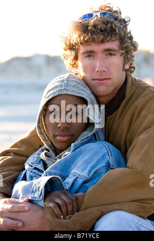Giovani interracial giovane seduti insieme sulla spiaggia Foto Stock