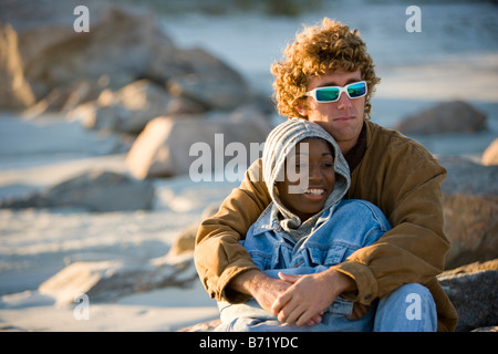 Giovani interracial giovane seduti insieme sulla spiaggia Foto Stock
