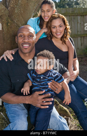 Felice famiglia americana africana seduti intorno all albero nel cortile all'aperto Foto Stock