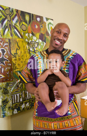 Felice americano africano padre vestito nei tradizionali costumi africani holding baby Foto Stock