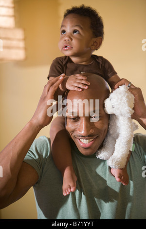 Felice americano africano azienda padre figlio bambino sulle spalle Foto Stock