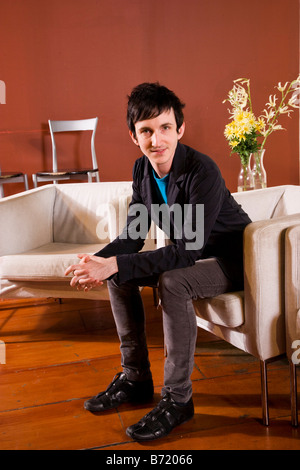 Elegante giovane uomo seduto in soggiorno moderno Foto Stock