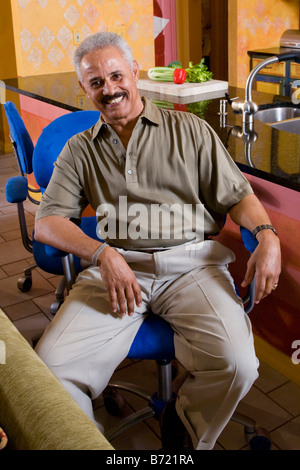 L'età media di afro-americano di uomo seduto di fronte a cucina Foto Stock