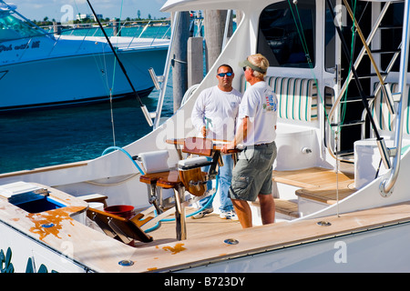 Palm Beach Shores , Marina, potenza motore pesci gioco barche da pesca ormeggiate al quay , uomini mazzo di pulizia dalla sedia di pesca Foto Stock