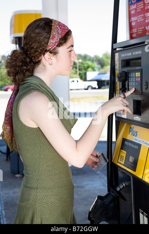 Giovane donna usa la sua carta bancomat per pagare la benzina Foto Stock