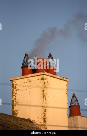 Il fumo proveniente da una famiglia camino sorge in mattina presto luce nel cielo blu contea di Down Irlanda del Nord Regno Unito Foto Stock