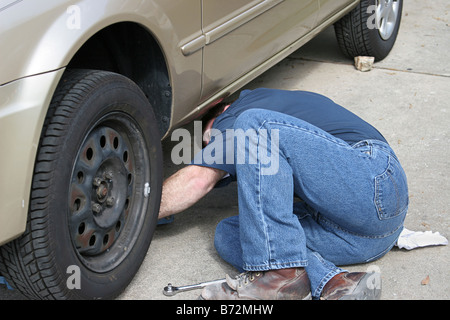 Un meccanico di raggiungere al di sotto di una automobile Foto Stock