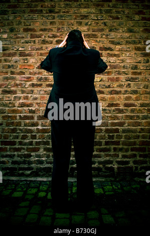 Business man in testa le mani di fronte al muro Foto Stock