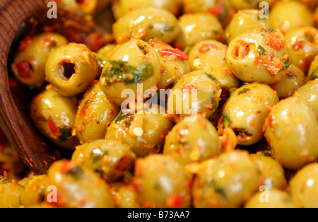Close-up di olive verdi marinato con peperoncino e erbe con legno cucchiaio su un mercato in stallo Foto Stock
