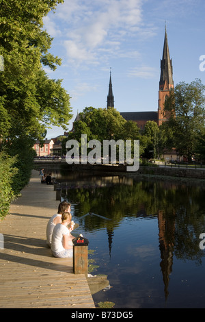 Le persone accanto al fiume Fyris e cattedrale di Uppsala Foto Stock