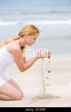 Donna di vagliatura sabbia attraverso le mani Foto Stock