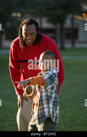 African American padre e figlio giocare a calcio nel parco Foto Stock