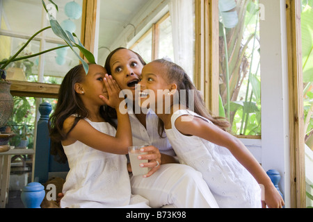 Felice afro-americano di madre e le sue figlie in veranda whispering Foto Stock