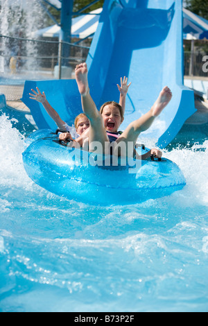 Ritratto di ragazze lo scorrimento verso il basso waterslide insieme su innertube in acqua park Foto Stock