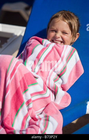 Giovane ragazza sulla sedia a sdraio avvolti in asciugamano Foto Stock
