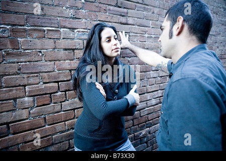 I giovani ispanici giovane parlando fuori appoggiato contro un muro di mattoni Foto Stock