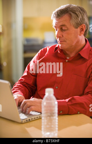 Di mezza età maschio lavoratore di ufficio lavora sul computer portatile Foto Stock