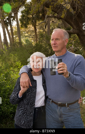 Coppia senior insieme rispettando la natura, tenendo il binocolo Foto Stock