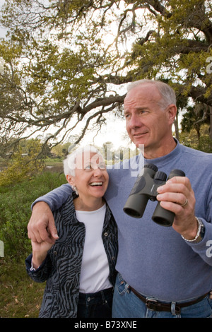 Coppia senior insieme rispettando la natura, tenendo il binocolo Foto Stock