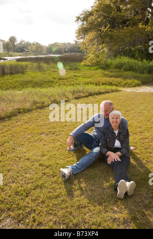 Coppia senior seduto sull'erba in posizione di parcheggio Foto Stock