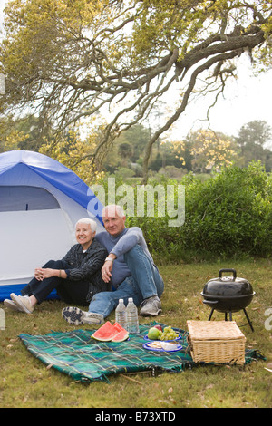 Coppia senior in seduta anteriore della tenda, camping in posizione di parcheggio Foto Stock