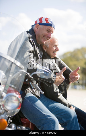 Felice senior biker giovane appoggiata contro la motocicletta Foto Stock