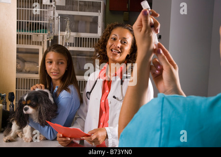 Assistente veterinario la preparazione di iniezione per cane mentre veterinario e proprietario di pet attendere Foto Stock