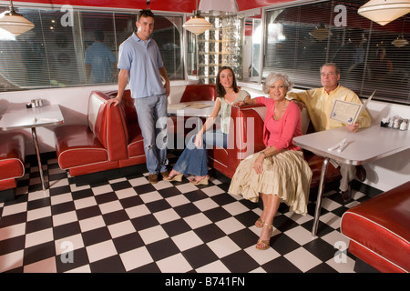 Coppia giovane con i genitori seduto in cabina di un vecchio stile diner Foto Stock