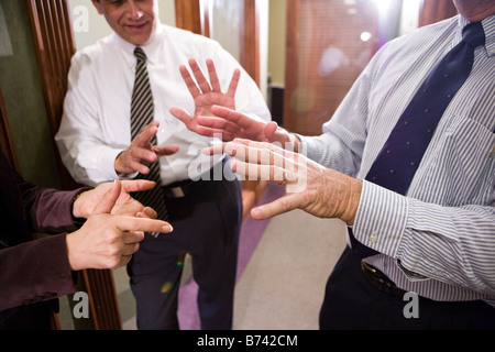 Sezione mediana di tre imprenditori aventi la discussione nel corridoio di office Foto Stock