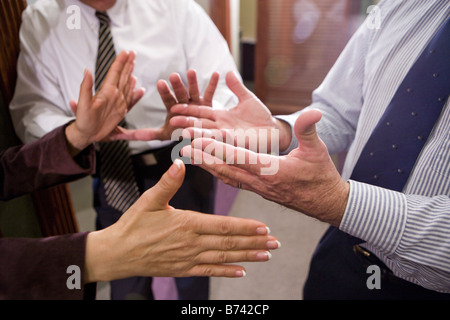 Sezione mediana di tre imprenditori aventi la discussione nel corridoio di office Foto Stock