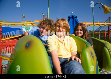 I bambini a cavallo di un roller coaster in un parco di divertimenti Foto Stock