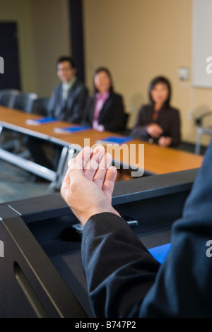 La sezione centrale dell'uomo dare la parola di fronte a uomini d'affari asiatici Foto Stock