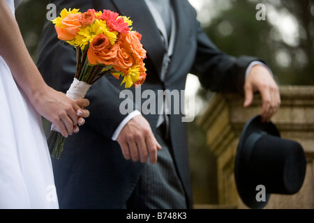 Close-up della sezione mediana della sposa e lo sposo holding bouquet e hat Foto Stock