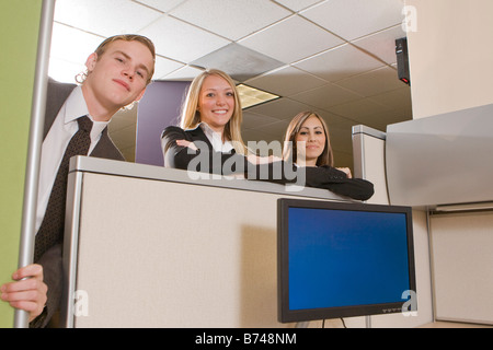 Tre giovani lavoratori ufficio appoggiata sulla partizione dell'armadio Foto Stock