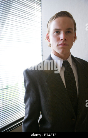 Giovane uomo nel business suit in piedi da una finestra Foto Stock