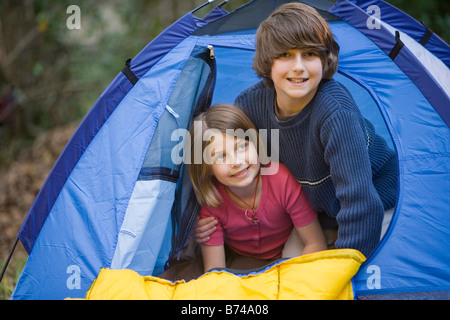 Ritratto di fratello e sorella peaking fuori dall'interno tenda Foto Stock