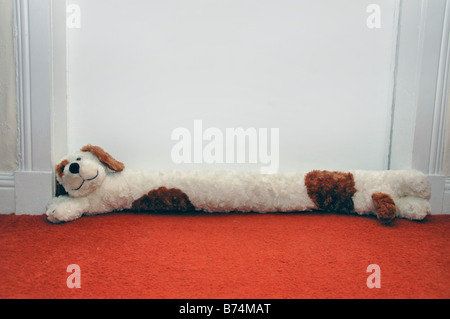 Una forma di cane dispositivo antispiffero sta alla base di una porta. Foto Stock